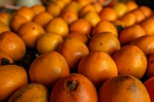 maturo arancia cachi. su il tavolo nel il mercato. un' mazzo di biologico cachi frutta a un' Locale agricoltori mercato nel dalat città, Vietnam. cachi sfondo. piatto posizione. foto