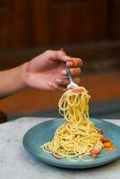 il mano quello è sollevamento il spaghetti su il piatto foto