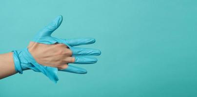 stretta di mano che indossa guanti medici strappati o guanti di gomma strappati su sfondo blu e verde o blu tiffany.coclor monotono. foto