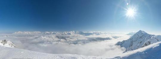vista aerea sopra le nuvole. località sciistica di rosa khutor, montagne coperte di neve a krasnaya polyana, russia.