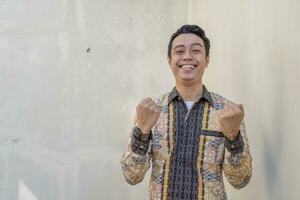 giovane indonesiano indossare batik tradizionale cultura Indonesia con Saluti gesto foto
