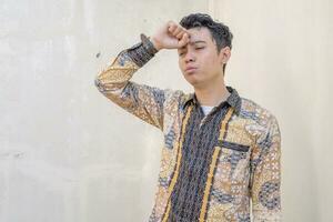 giovane indonesiano indossare batik tradizionale cultura Indonesia con frustrazione gesto foto
