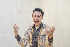 giovane indonesiano indossare batik tradizionale cultura di Indonesia con rabbia gesto. foto