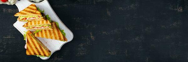 club Sandwich con prosciutto, pomodoro, verde e formaggio. grigliato Panini. superiore Visualizza foto