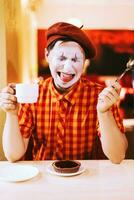il clown è mangiare un' torta nel un' bar e il suo viso è gracchiare. foto