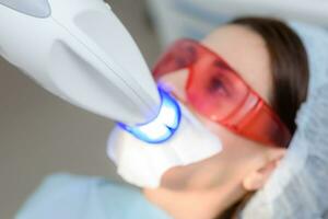 il paziente subisce un' procedura per denti imbiancamento con un ultravioletto lampada foto