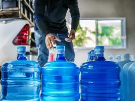 potabile acqua chiaro e pulito nel blu gallone disposte nel un' riga preparare per sollevamento in il indietro di un' trasporto camion purificato potabile acqua dentro il produzione linea piccolo attività commerciale foto