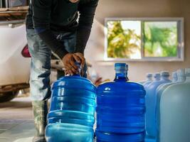 potabile acqua chiaro e pulito nel blu gallone disposte nel un' riga preparare per sollevamento in il indietro di un' trasporto camion purificato potabile acqua dentro il produzione linea piccolo attività commerciale foto