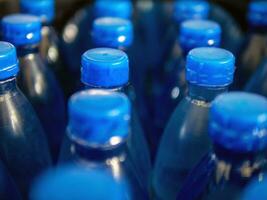 avvicinamento di grande numero di confezionato blu in bottiglia potabile acqua con blu tappi.bere acqua bottiglia sfondo foto