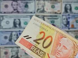 approccio alla banconota brasiliana di venti reais e sfondo con banconote da un dollaro americano foto