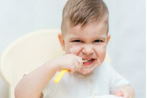 carino bambino piccolo mangiare un' zucca con un' piccolo cucchiaio lui stesso foto