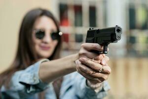 ragazza con un' pistola su il strada impara per sparare foto