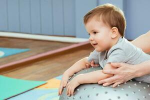 poco bambino giochi con un' fitball nel il Palestra foto