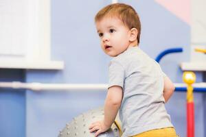 poco bambino giochi con un' fitball nel il Palestra foto