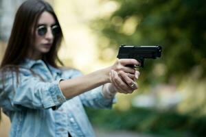 ragazza con un' pistola su il strada impara per sparare foto