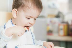 bambino nel il cucina mangiare frutta puré foto