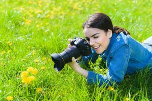 attraente ragazza nel un' prato prende immagini di fiori foto