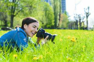 attraente ragazza nel un' prato prende immagini di fiori foto