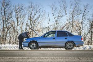 uomo riparazione un' auto in piedi a il cappuccio foto