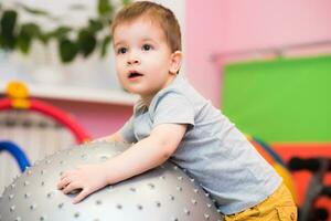 poco bambino giochi con un' fitball nel il Palestra foto