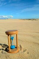 un clessidra seduta su il sabbia nel il mezzo di un' deserto foto