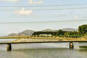 un' ponte spanning il fiume con un' montagna nel il sfondo foto