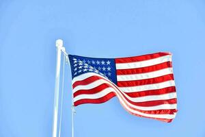 un americano bandiera volante nel il vento contro un' blu cielo foto