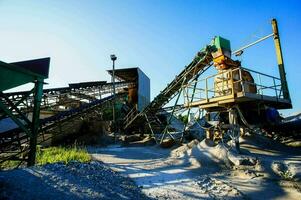 un' grande trasportatore cintura è nel il mezzo di un' ghiaia fossa foto