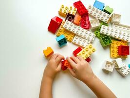 bambino giocando con colorato edificio blocchi su bianca sfondo. superiore Visualizza foto