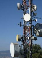 telecomunicazione antenna con multiplo satellitare contro il blu cielo foto