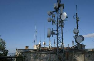 telecomunicazione antenna con multiplo satellitare contro il blu cielo foto