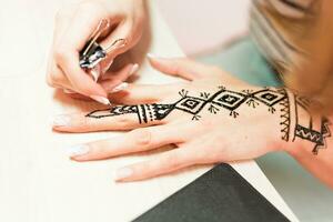 artista l'applicazione alcanna tatuaggio su donne mani. mehndi è tradizionale indiano decorativo arte. avvicinamento foto