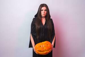 donna come strega è in piedi con il zucca nel il studio. Halloween e carnevale concetto foto