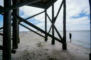 un' uomo in piedi sotto un' di legno struttura su il spiaggia foto