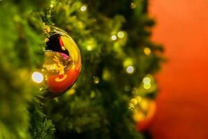 d'oro Natale palle decorato su pino albero con sfocato Natale illuminazione su rosso sfondo foto