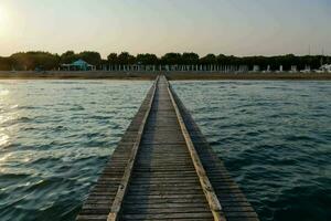 un' di legno molo conduce per il oceano a tramonto foto