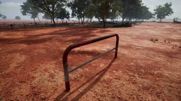 un' rustico rosso sporco campo con un' affascinante recinto e alberi nel il sfondo foto