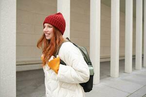 contento testa Rossa ragazza, turista andando in giro cittadina, esplorando sospiro posti nel città, backpacking in giro Europa, gode in viaggio foto