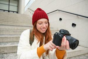 ritratto di femmina fotografo a piedi in giro città con professionale telecamera, assunzione immagini cattura urbano colpi, Fotografare all'aperto foto