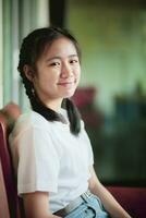 sorridente viso asiatico adolescente seduta casa vivente camera foto