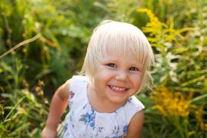 bambina in abito estivo guarda in una macchina fotografica foto