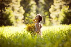 bambina in piedi con un mazzo di fiori gialli foto