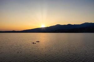 sagoma di due kajak in mezzo al lago al tramonto foto