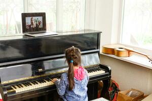 casa lezione su musica per il ragazza su il pianoforte. il idea di attività per il bambino a casa durante quarantena. musica concetto foto