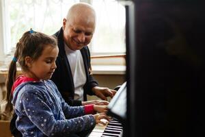 nonno insegnare ragazza giocando il pianoforte felicemente foto