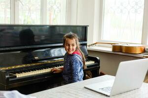 casa lezione su musica per il ragazza su il pianoforte. il idea di attività per il bambino a casa durante quarantena. musica concetto foto