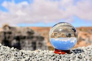 un' cristallo palla seduta su superiore di un' roccia foto