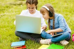 Due bellissimo sorelle fare loro compiti a casa durante quarantena. bambini uso gadget per apprendimento. formazione scolastica, distanza apprendimento, casa istruzione durante quarantena foto