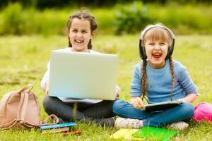 Due divertente studentesse sedersi su il erba e leggere libri. ragazze, amiche, sorelle siamo insegnato Lezioni nel natura. foto