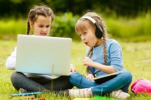 Due divertente studentesse sedersi su il erba e leggere libri. ragazze, amiche, sorelle siamo insegnato Lezioni nel natura. foto